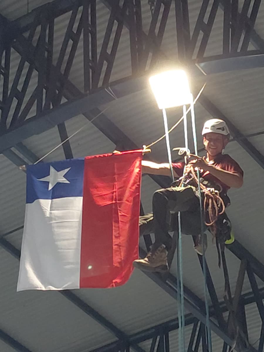 Técnico fixando a bandeira do Chile na estrutura do ginásio