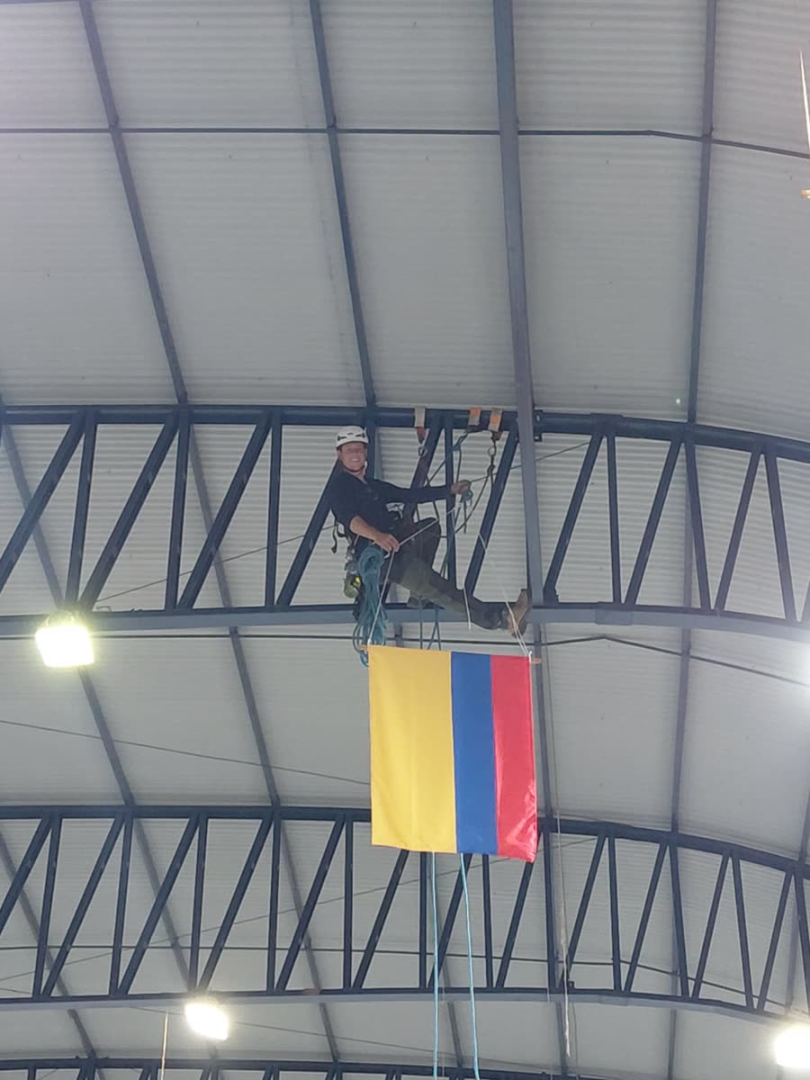 Técnico na treliça após instalar a bandeira da Colômbia