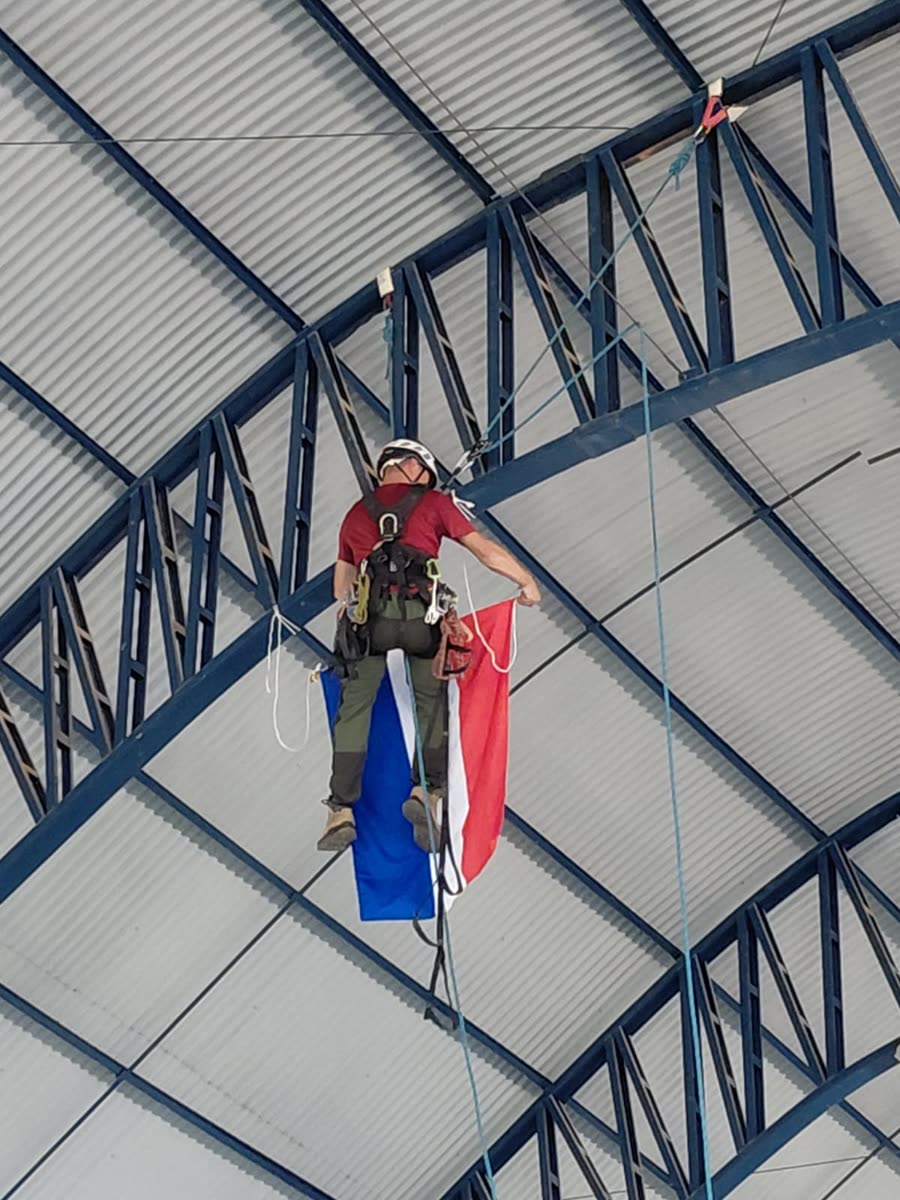 Técnico fixando bandeira na estrutura metálica da cobertura