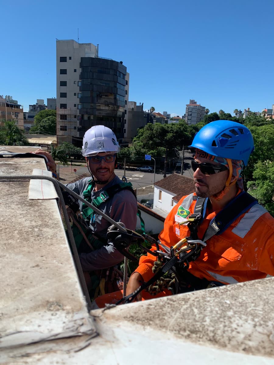 Equipe em acesso por cordas na platibanda de um prédio